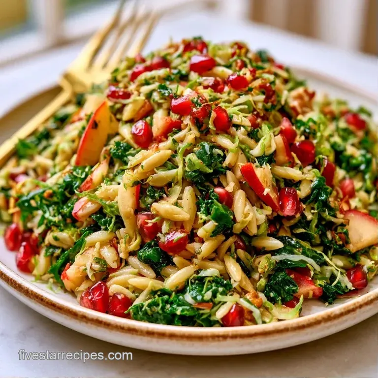 A ceramic bowl filled with ivory orzo, vibrant red apple chunks, and snowy feta crumbles topped with fresh parsley