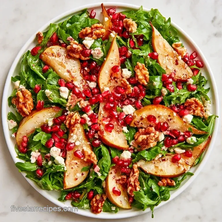 A white ceramic bowl filled with fresh greenery, pale pear wedges, and bright red pomegranate jewels.