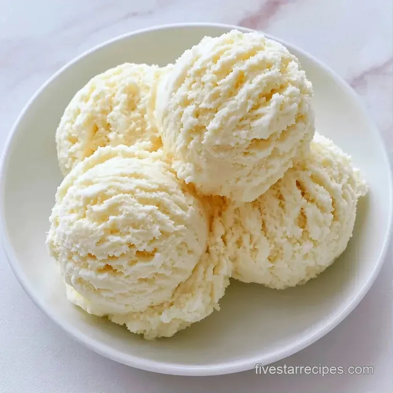 Three elegant scoops of ivory cream in a crystal glass bowl topped with a mint leaf and a single fresh raspberry.