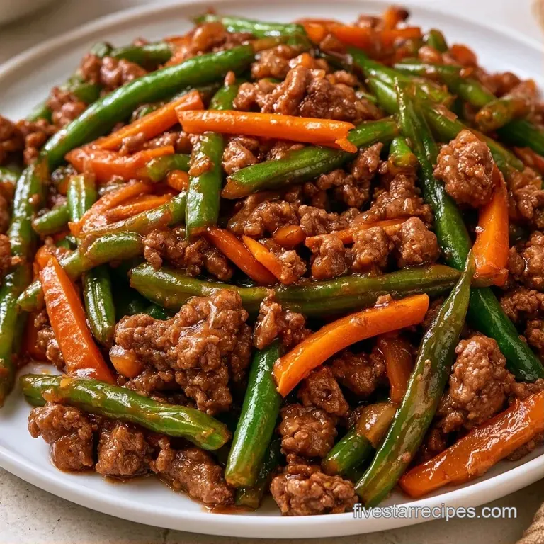 Elegant white plate holding vivid green Baguio beans tangled with bright orange carrot strips and tender beef crumbles.