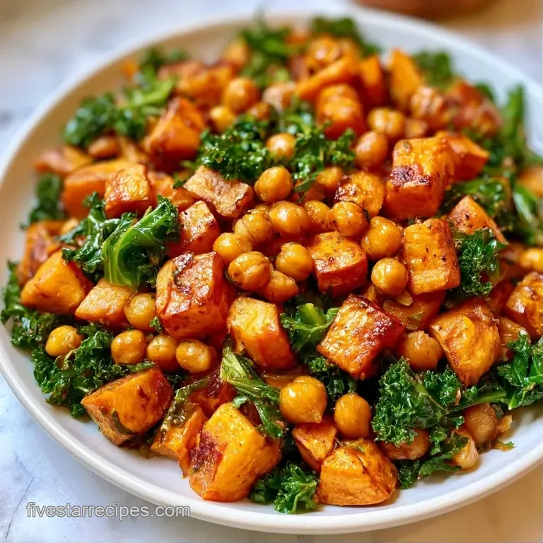 Roasted orange cubes and deep green leaves arranged in a white bowl with golden chickpeas and toasted seed garnish.